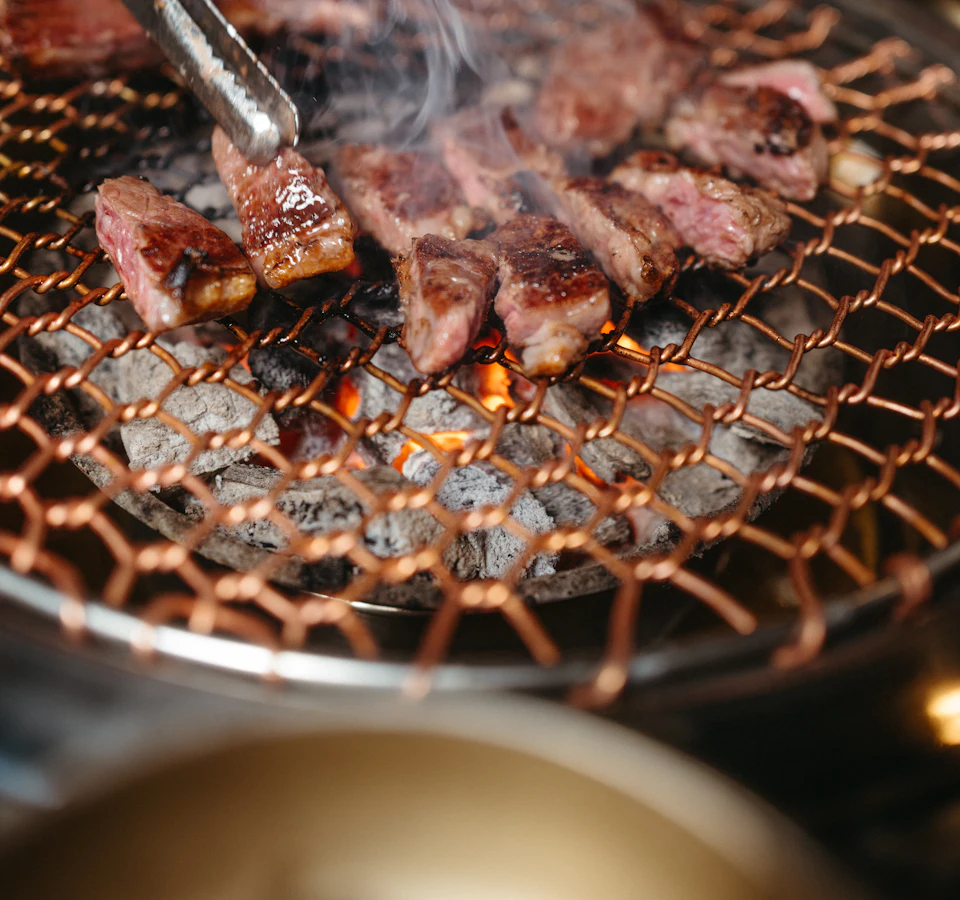 熾火の上の網で、和牛を焼いている。煙が立ちのぼる